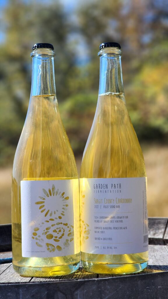 A picture of two bottles of Skagit County Chardonnay made by Garden Path Fermentation outside in the sun.